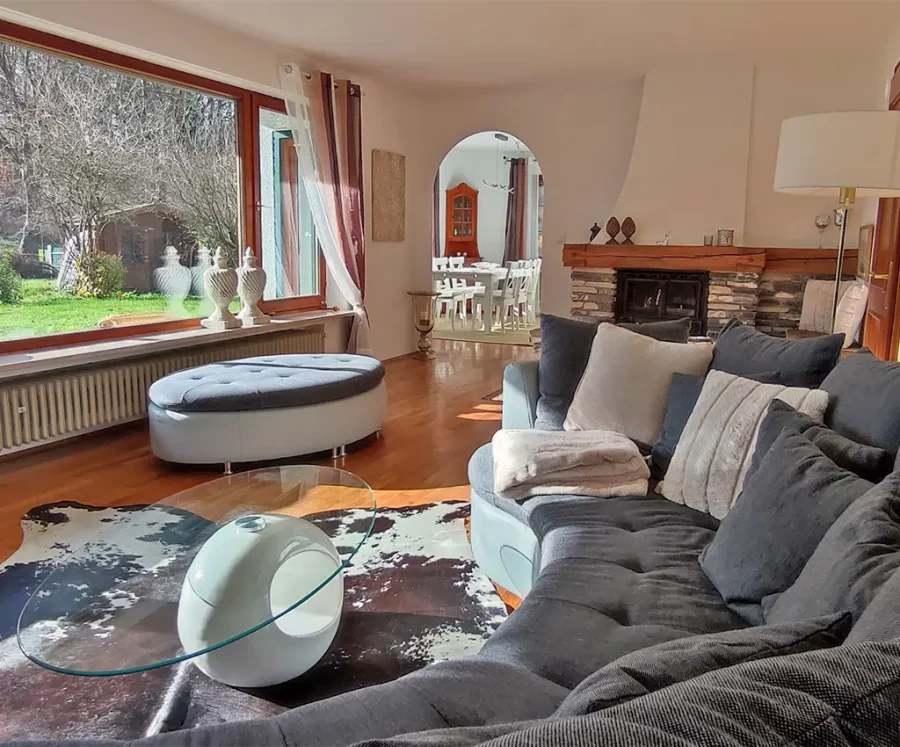Ferienhaus Happyness Wohnbereich mit großem Sofa, Blick ins Esszimmer, und Kamin